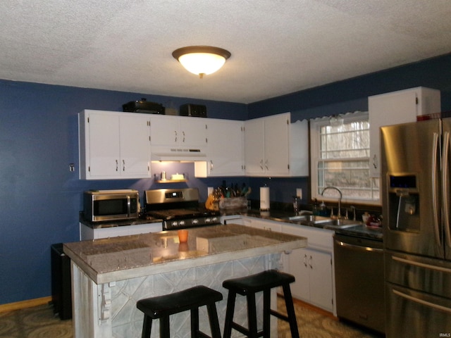 kitchen featuring stainless steel appliances, white cabinetry, sink, and a kitchen bar