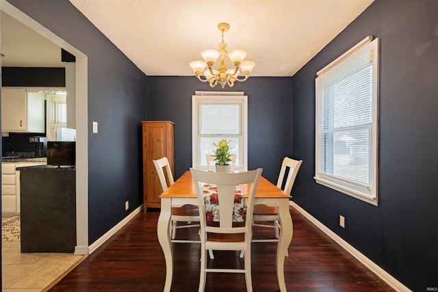 dining room with dark wood-type flooring and a chandelier