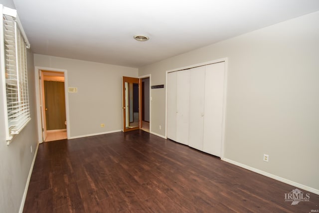 unfurnished bedroom with dark hardwood / wood-style flooring and a closet