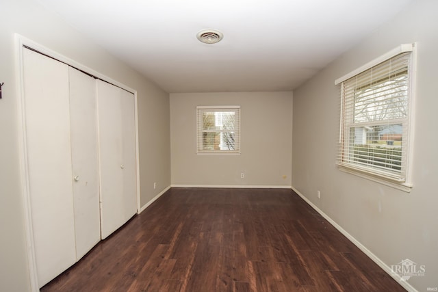 unfurnished bedroom with dark hardwood / wood-style floors and a closet