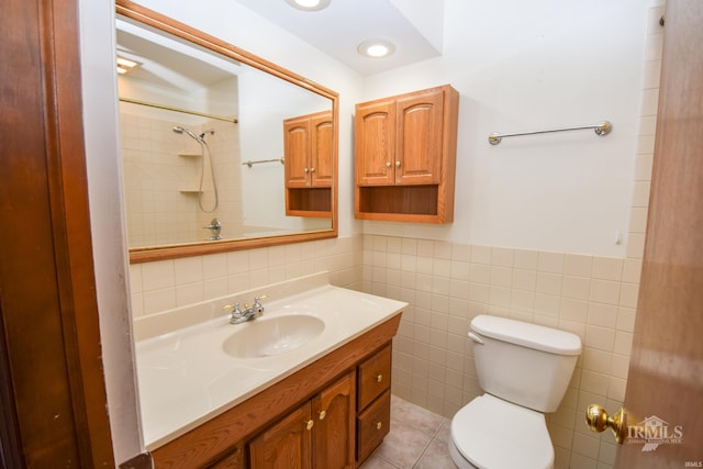 bathroom featuring tile walls, vanity, tiled shower, toilet, and tile patterned floors