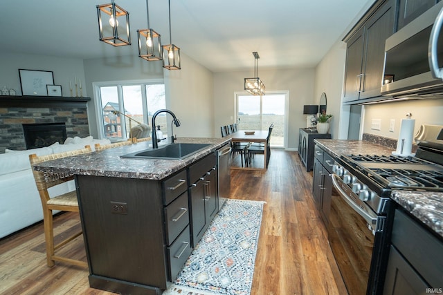 kitchen featuring sink, hanging light fixtures, appliances with stainless steel finishes, a healthy amount of sunlight, and a kitchen island with sink