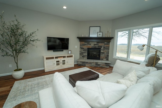 living room with dark hardwood / wood-style flooring and a stone fireplace