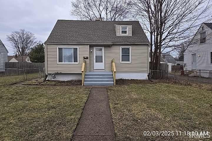 view of front of home featuring a shingled roof, a front yard, and fence