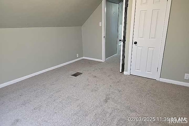 bonus room with lofted ceiling and light carpet