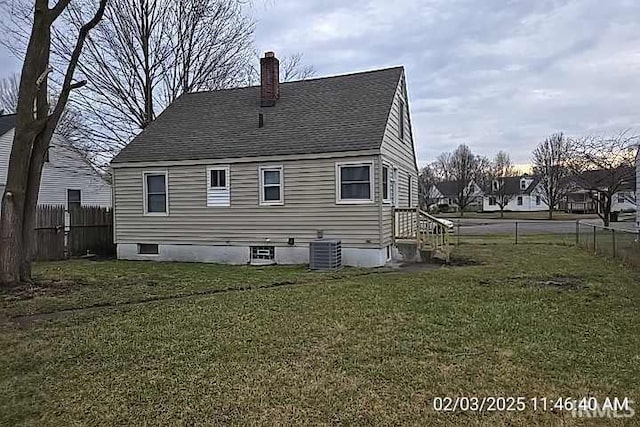 rear view of house with central air condition unit and a lawn