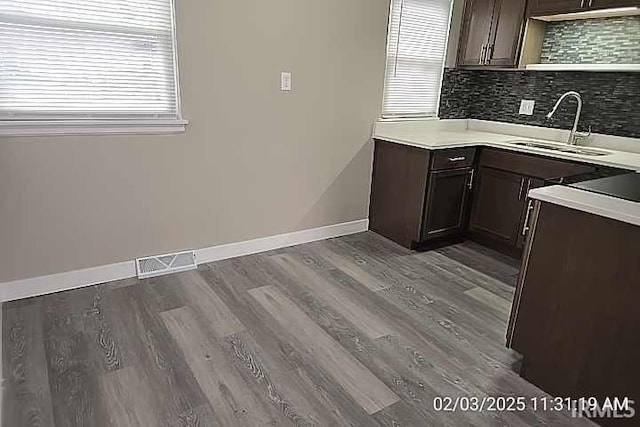 kitchen with tasteful backsplash, sink, hardwood / wood-style flooring, and dark brown cabinets