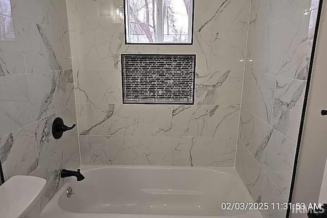 bathroom featuring toilet and tiled shower / bath