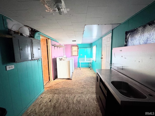 kitchen featuring washer / dryer, electric panel, and wood walls