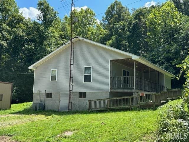 back of property with a deck, central AC unit, and a lawn