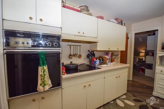 kitchen featuring wall oven, black stovetop, and dark hardwood / wood-style floors