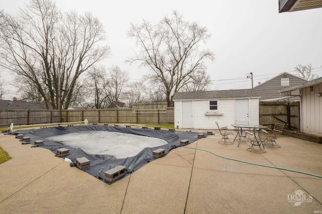 view of patio / terrace featuring a covered pool and a storage unit