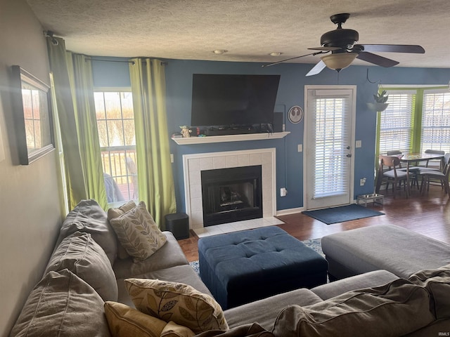 living room featuring a tiled fireplace, hardwood / wood-style flooring, a wealth of natural light, and a textured ceiling