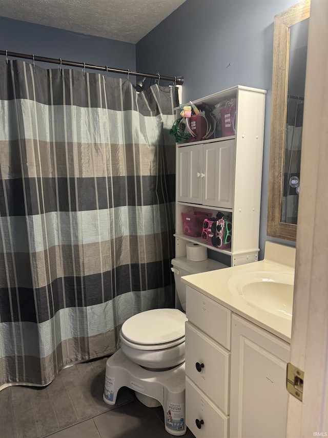 bathroom featuring tile patterned flooring, vanity, a textured ceiling, and toilet