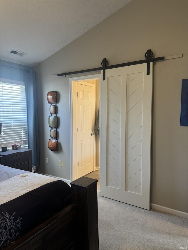 carpeted bedroom featuring a barn door and vaulted ceiling