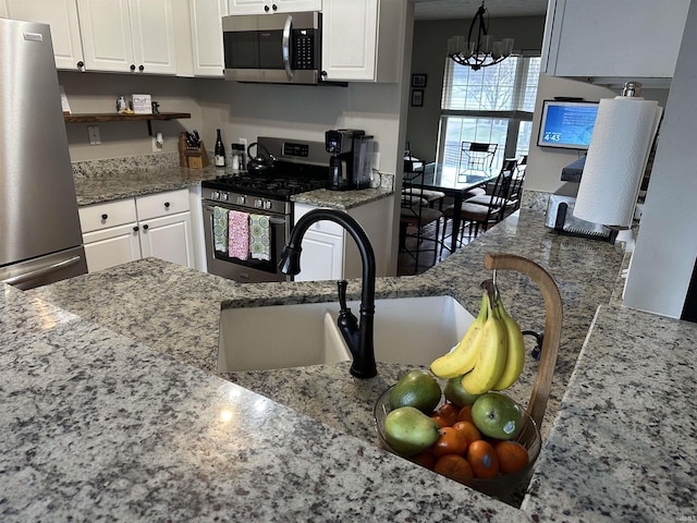 kitchen with appliances with stainless steel finishes, stone countertops, and white cabinets