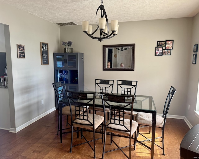 dining room featuring a textured ceiling, dark hardwood / wood-style floors, and a chandelier