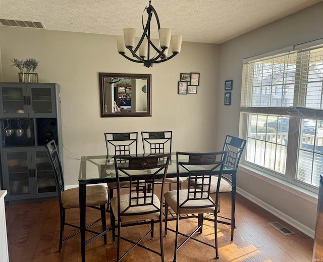 dining room with an inviting chandelier, dark wood-type flooring, and a textured ceiling