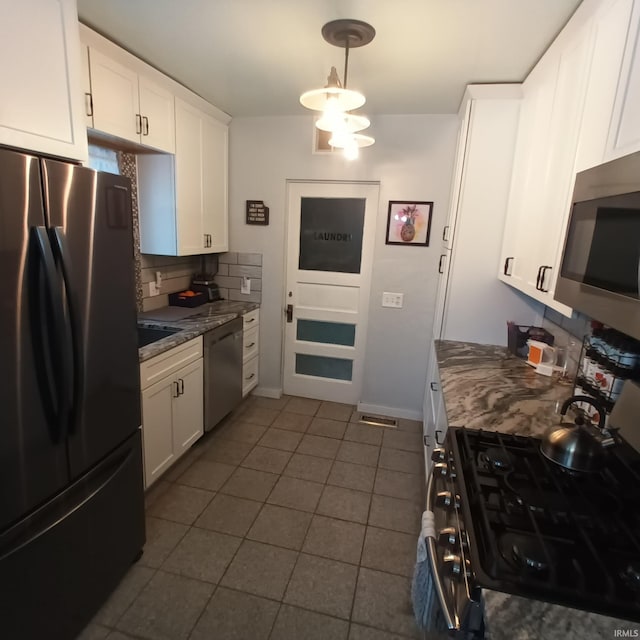 kitchen with decorative backsplash, dark tile patterned floors, white cabinets, and appliances with stainless steel finishes