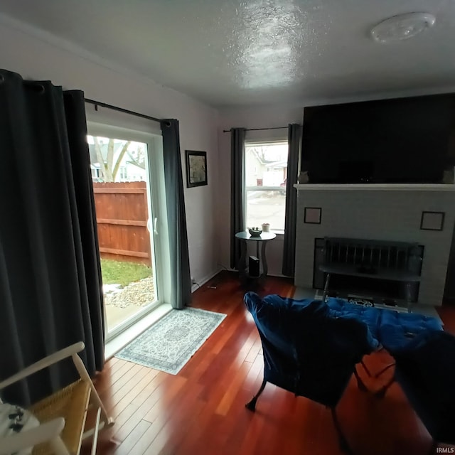 living room featuring dark hardwood / wood-style flooring, a large fireplace, and a textured ceiling