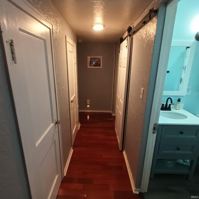 hall with dark hardwood / wood-style flooring, sink, and a barn door