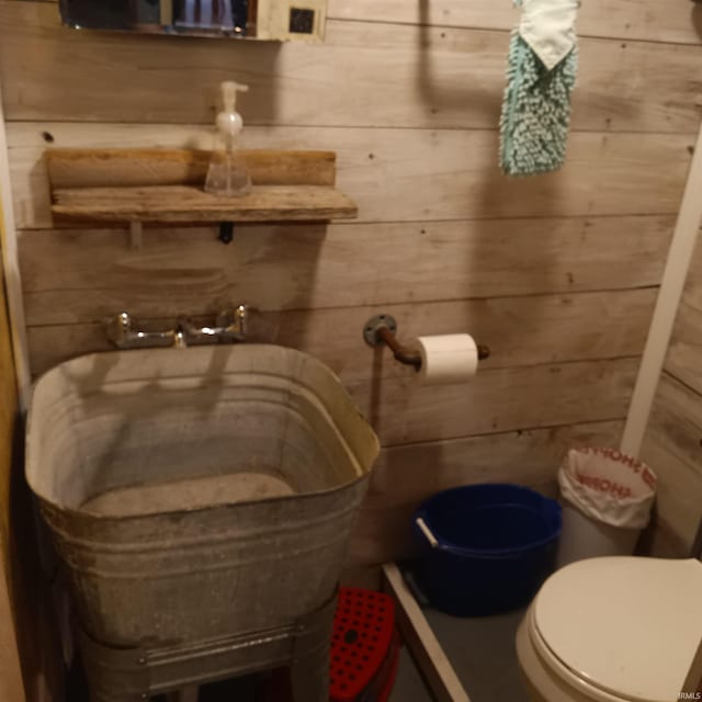 bathroom with toilet and wood walls