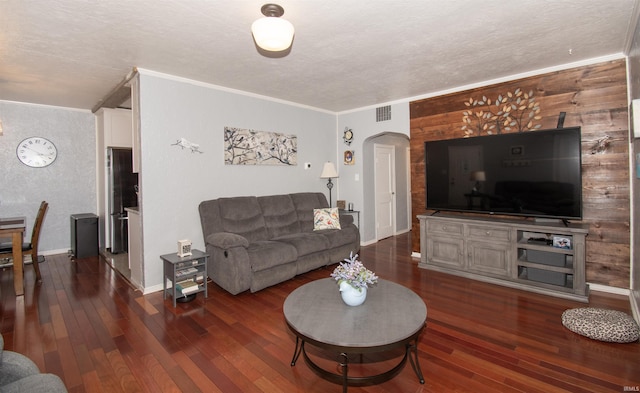 living room with crown molding, dark wood-type flooring, and a textured ceiling