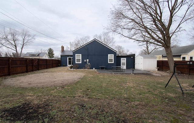 rear view of property featuring a storage shed, a lawn, and a patio