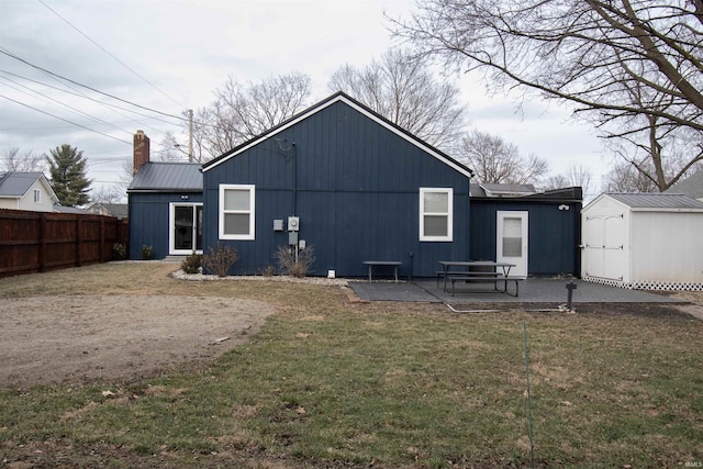 rear view of property featuring a storage shed, a lawn, and a patio area