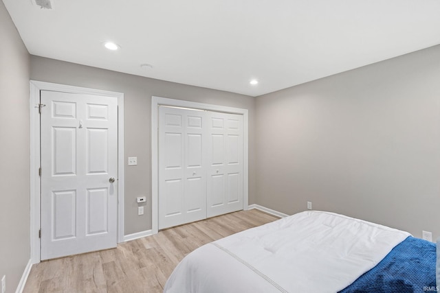 bedroom with light hardwood / wood-style floors and a closet