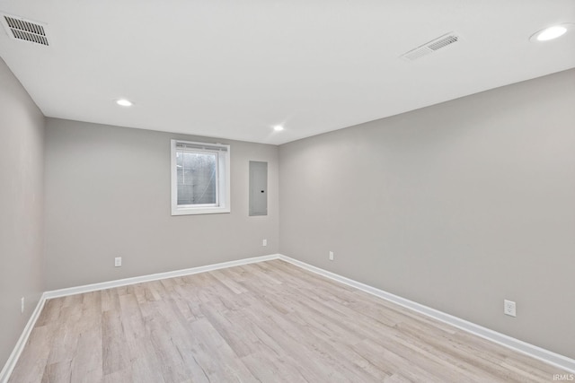 empty room featuring electric panel and light wood-type flooring