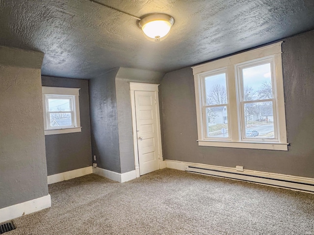 additional living space featuring lofted ceiling, a baseboard heating unit, carpet floors, and a textured ceiling