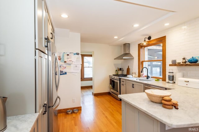 kitchen with wall chimney exhaust hood, sink, tasteful backsplash, light wood-type flooring, and stainless steel range with gas stovetop