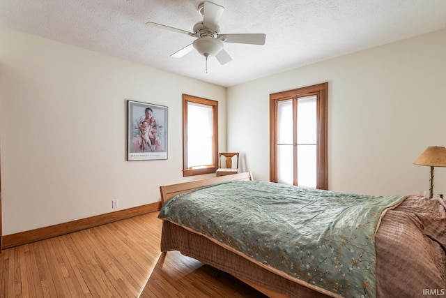 bedroom featuring ceiling fan, hardwood / wood-style flooring, and a textured ceiling