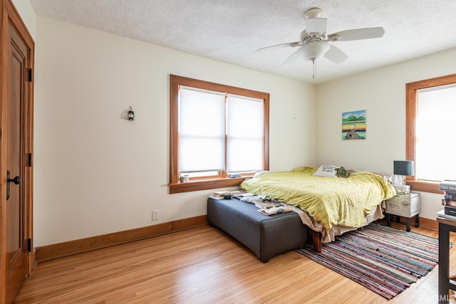 bedroom featuring ceiling fan, light hardwood / wood-style flooring, and a textured ceiling