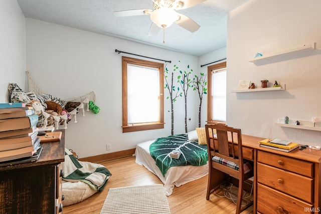 bedroom featuring multiple windows, a textured ceiling, and light wood-type flooring