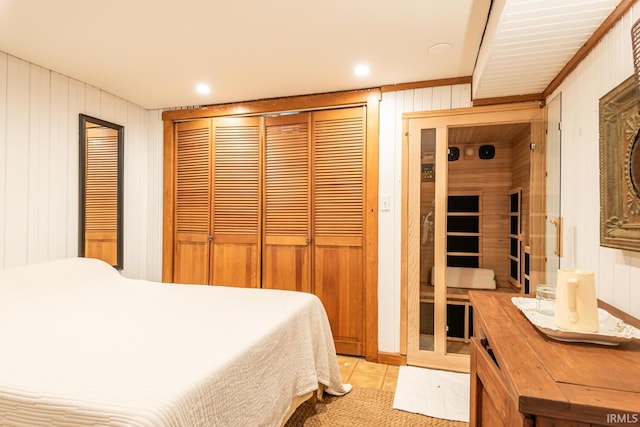 tiled bedroom featuring wooden walls and a closet