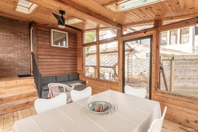 sunroom / solarium featuring ceiling fan, a skylight, and wooden ceiling