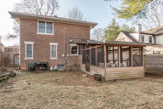 rear view of property featuring a yard and a sunroom