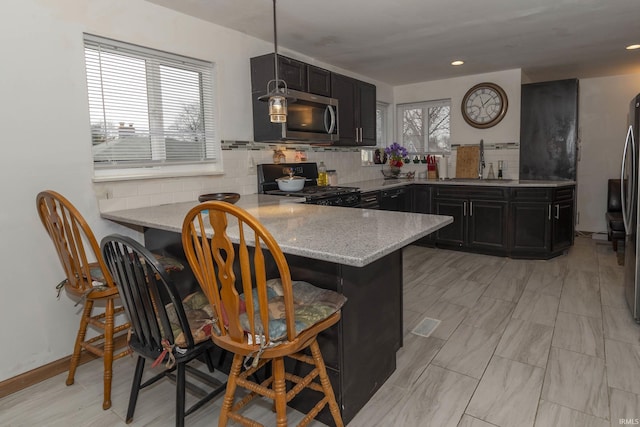 kitchen featuring stainless steel appliances, sink, a breakfast bar, and kitchen peninsula