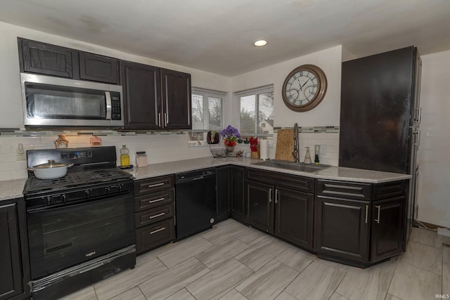 kitchen featuring backsplash, light stone countertops, sink, and black appliances