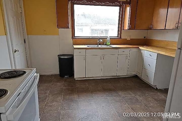 kitchen featuring white cabinetry, sink, stainless steel refrigerator, and electric stove