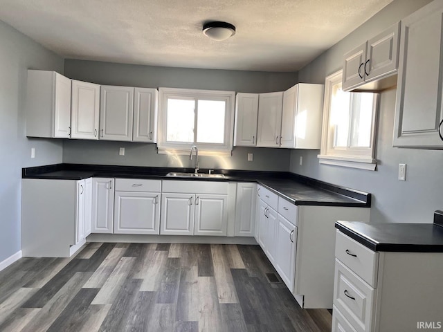 kitchen with sink, a textured ceiling, white cabinets, and dark hardwood / wood-style floors