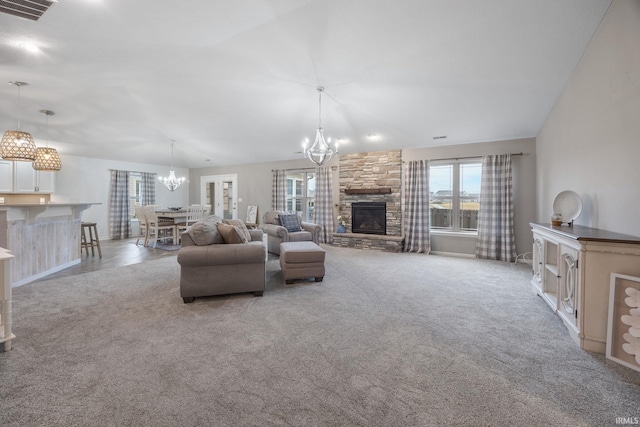 unfurnished living room featuring light carpet, a stone fireplace, and a chandelier