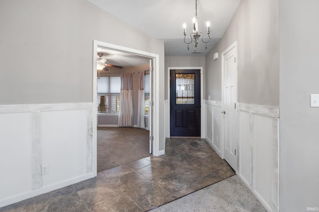 carpeted entrance foyer featuring an inviting chandelier