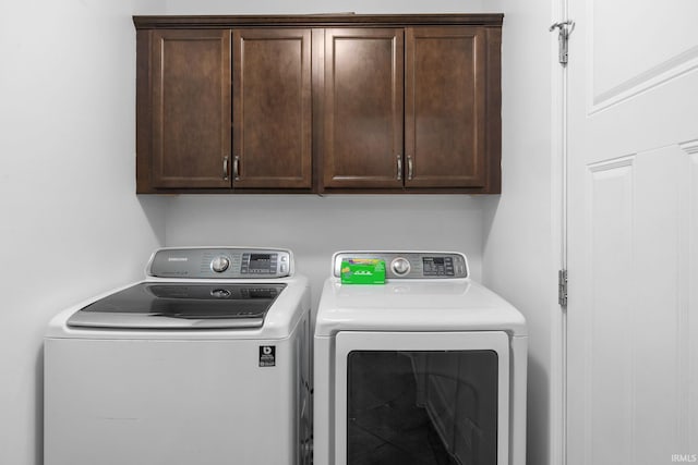 clothes washing area with cabinets and separate washer and dryer