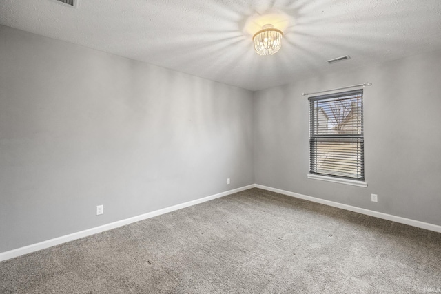 empty room featuring an inviting chandelier, a textured ceiling, and carpet