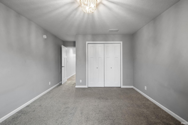 unfurnished bedroom featuring light colored carpet, a textured ceiling, and a closet