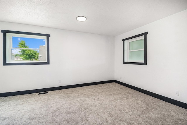 spare room featuring a textured ceiling and carpet