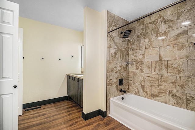 bathroom with vanity, hardwood / wood-style floors, and tiled shower / bath combo